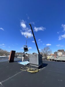 Cambridge AC repair team using a crane to install a rooftop commercial air conditioning unit.